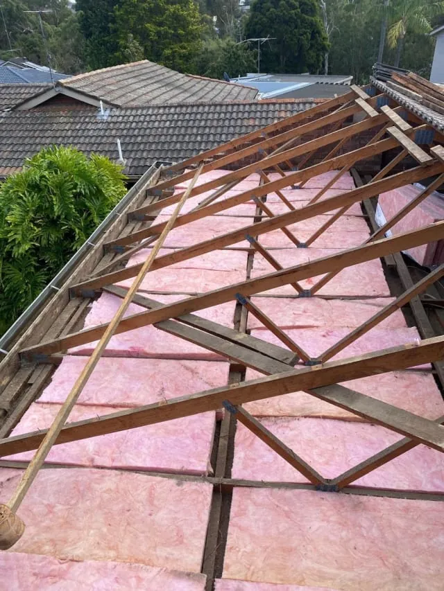 Roofer repairing tiles on a pitched roof in Melbourne